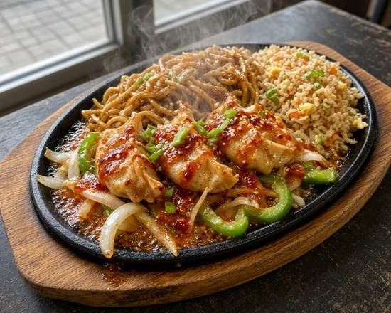 Momos in red chilli sauce on noodles and fried rice on a sizzling cast-iron plate with onion and green pepper